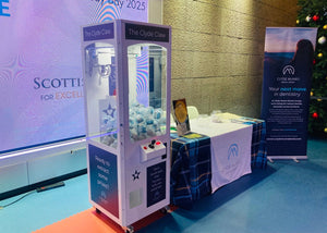 claw machine at a Scottish Dental Association event with promotional materials in the background.